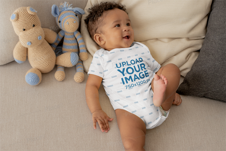 onesie mockup of a cute baby boy lying in bed with stuffed